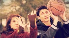 a man and woman holding up basketballs in front of their faces while looking at the camera