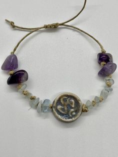 Ohm amethyst on adjustable hemp bracelet Beach Jewelry With Sliding Knot In Purple, Beach Jewelry With Purple Sliding Knot, Purple Jewelry With Sliding Knot For Beach, Adjustable Lavender Spiritual Bracelets, Adjustable Lavender Bohemian Jewelry, Adjustable Bohemian Lavender Jewelry, Adjustable Lavender Bracelets For Beach, Adjustable Amethyst Beaded Bracelets, Adjustable Amethyst Bracelets For Healing