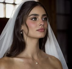 a woman in a wedding dress with a veil on her head and wearing a diamond necklace