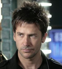 a close up of a person wearing a black shirt and looking at the camera with a serious look on his face