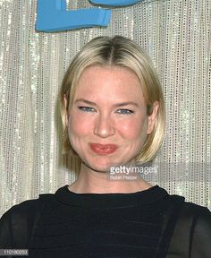 a woman with blonde hair and blue eyes smiles at the camera while standing in front of a