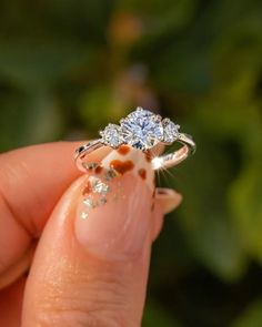 a woman's hand holding an engagement ring with two diamonds on the top and bottom