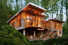 a modern house in the woods with stairs leading up to it's second story