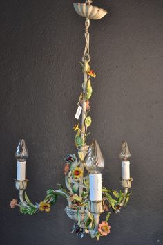 a chandelier hanging from the ceiling in a room with dark walls and flowers on it