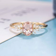 an engagement ring with a pink diamond surrounded by white diamonds on a blue table top