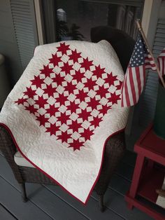 a red and white quilt sitting on top of a chair next to an american flag