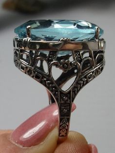 24ct. Simulated Aquamarine Sterling Silver RingOval Beast Design#D76 This is a new beautiful Victorian reproduction ring cast in solid sterling silver. The gorgeous filigree ring is set with a huge approximately 24 carat simulated blue aquamarine gemstone. The stunning gem is 17mm (11/16") wide x 23mm(15/16") long. The ring is 12mm off the finger. The inside of the band is marked 925 for sterling silver. Notice the craftmanship of the sterling silver setting. The large stone is accented by the b Formal Oval Engraved Filigree Ring, Victorian Oval Filigree Ring As Gift, Ornate Silver Topaz Ring For Gift, Formal Silver Engraved Ring With Gemstone, Art Deco Oval Filigree Ring With Gemstone, Oval Hallmarked Filigree Ring For Collectors, Silver Engraved Ring With Gemstone For Formal Occasions, Elegant Oval Sterling Silver Engraved Ring, Elegant Oval Engraved Sterling Silver Ring