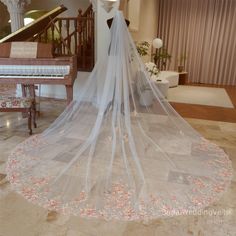 a wedding veil is hanging from the ceiling in front of a grand piano and chandelier