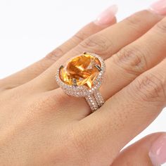 This exquisite ring features a stunning Citrine as the center stone, radiating vibrant hues of golden yellow. The Citrine is complemented by an array of White Zircon accent stones, adding a touch of brilliance and sparkle to the piece. The design showcases a luxurious rose gold-plated band, enhancing the warm tones of the Citrine. The intricate setting highlights the gemstone's natural beauty, making it a perfect statement piece for any occasion. This piece is inspired by the Art Deco era, known Dazzling Oval Yellow Ring, Dazzling Yellow Oval Ring, Luxury Gold Rings With Gemstone Accents, Gold Topaz Crystal Ring With Gemstone, Yellow Open Ring Fine Jewelry, Luxury Orange Gemstone Ring, Luxury Citrine Rings For Anniversary, Yellow Diamond Gemstone Ring Fine Jewelry, Elegant Citrine Crystal Ring