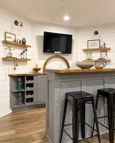 a kitchen with two bar stools and a flat screen tv mounted on the wall