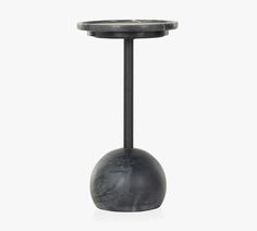 a black table with a metal base and a round top on the bottom, against a white background