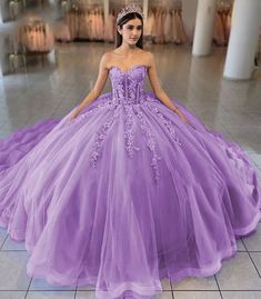 Turn your quinceanera into a fairytale with this exquisite ball-gown style dress. This dress is designed in airy tulle and available in dreamy colors like sky blue, lilac, and pink. The sweetheart neckline beautifully frames the shoulders and neckline, enhancing your look with a touch of romance. Adorned with intricate appliques and delicate 3D floral embellishments, this dress brings an enchanting garden to life. The lace-up back ensures a perfect fit, while the sleeveless design allows for gra Lilac And Pink Quinceanera Dresses, Lilac And Pink Quinceanera, Princess Tulle Quinceanera Dress For Sweet 16, Tulle Quinceanera Dress For Prom Season, Lavender Ball Gown For Quinceanera, Princess Style Tulle Quinceanera Dress, Tulle Quinceanera Ball Gown Dress, Tulle Quinceanera Dress Ball Gown, Purple Tulle Gown For Quinceanera