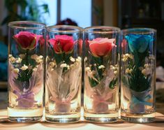 four vases with flowers in them sitting on a table top next to each other