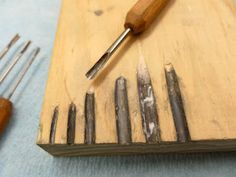 a wooden cutting board topped with lots of metal tools next to a set of screwdrivers