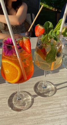 two glasses filled with drinks sitting on top of a table