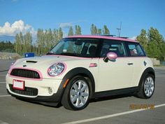 a white and pink mini car parked in a parking lot next to some trees on a sunny day