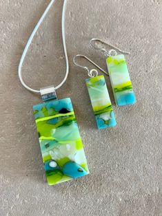 three pieces of glass sitting on top of a carpeted floor next to a necklace and earring