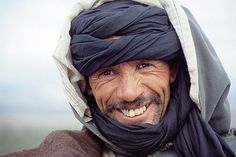 a man wearing a turban and smiling for the camera with his head wrapped around him