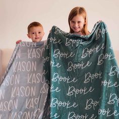 two children wrapped up in blankets with names on them, one boy and the other girl