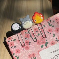 three little pins sitting on top of a pink bag