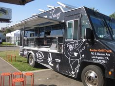 the food truck is parked on the side of the road in front of some orange chairs