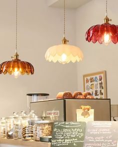 some lights hanging from the ceiling above a counter with donuts and other items on it