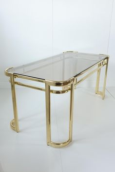 a glass table with gold legs on a white floor