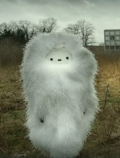 a white stuffed animal standing in the middle of a field