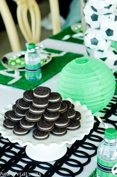 a table topped with lots of cookies on top of a white plate next to green paper lanterns