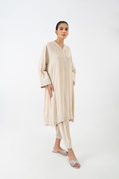 Introducing an exquisite ensemble consisting of a medium-length shirt in a pristine ivory shade, made from pure crepe silk. The shirt is meticulously handworked in self shades, featuring delicate details of resham, kora, and sequins throughout. The front and back of the shirt are fully adorned with this intricate work. To complete the ensemble, it is paired with a matching skinny shalwar, which also features matching work on the bottom. Delicate Details, Medium Length, Shades, Silk, Pure Products