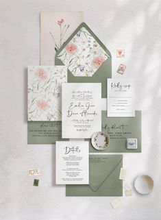 the wedding stationery is laid out on top of each other, including envelopes and cards