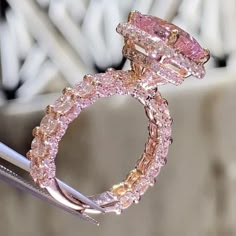 a pink diamond ring sitting on top of a piece of metal