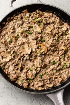 a skillet filled with mushroom and meat mixture on top of a white countertop