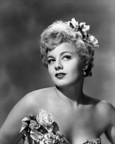 an old black and white photo of a woman wearing a dress with flowers in her hair