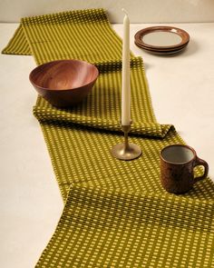 a table topped with plates and cups on top of a white table cloth next to a candle