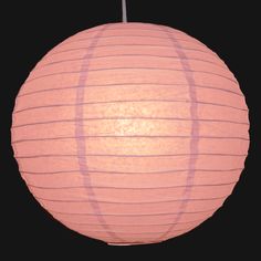 a pink paper lantern hanging from a black background