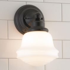 a light that is on the side of a white brick wall next to a toilet paper roll