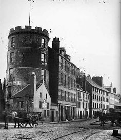 an old black and white photo of a horse - drawn carriage in front of buildings