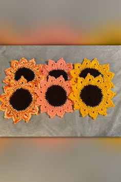 three crocheted doilys with black and yellow flowers on them, sitting on a gray surface