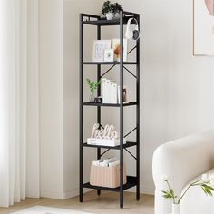 a black shelf with books and magazines on it next to a white chair in a living room