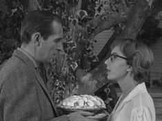 a man and woman holding a cake in their hands