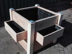 two wooden planters sitting next to each other on top of a cement ground near a building