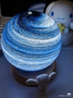 a small blue and white ball sitting on top of a table next to a laptop