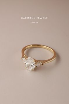 a yellow gold ring with three stones on it, and the words harmony jewels written in white