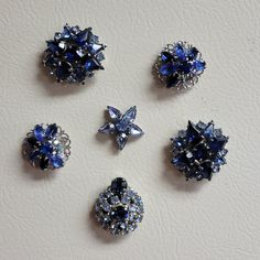 four blue and white brooches are arranged on a table