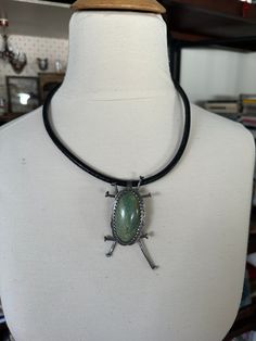 a necklace on a mannequin wearing a black choker with a green stone in the center