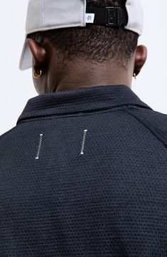 the back of a man's head wearing a white hat and black shirt with silver letters on it