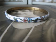 This is a beautiful vintage white cloisonne bracelet from the 1970's. It measures 7mm wide x 3mm thick. It is 2 5/8'' across on the inside, and 8'' around the inside. It is in good vintage condition with a Shabby Oriental grace. Perfect as a gift to a bride, or add it to your sweet collection. Vintage White Bangle For Wedding, Vintage White Wedding Bangle, Vintage White Bangle Bracelets, Vintage White Handmade Bangle, Collectible White Bracelet Jewelry, Adjustable White Vintage Bangle, Cloisonne Bracelet, Art Deco Locket, Wedding Tokens