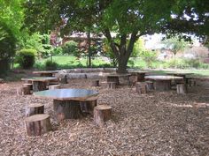 a group of wooden tables and benches in a park area with mulch on the ground