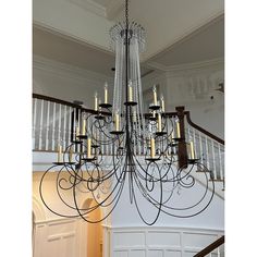 a large chandelier hanging from the ceiling in a room with white walls and stairs